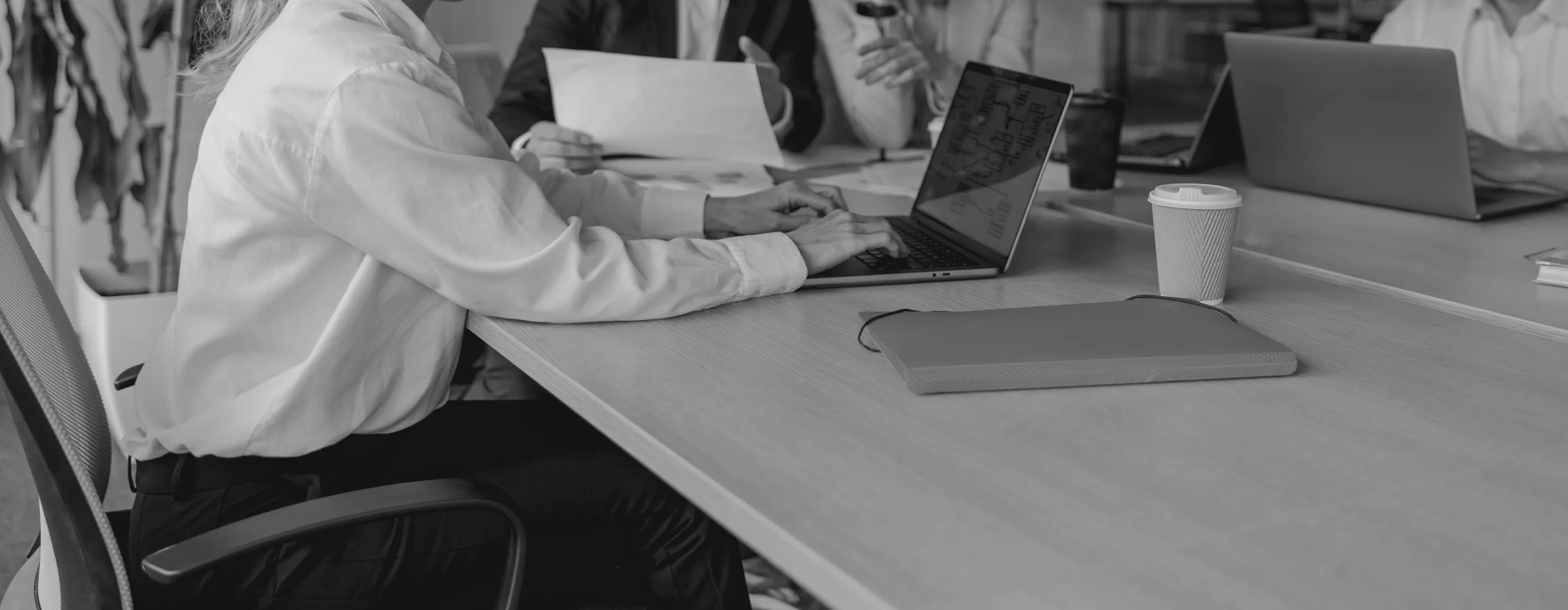 Group of people in a professional setting, with laptops and documents on the table.