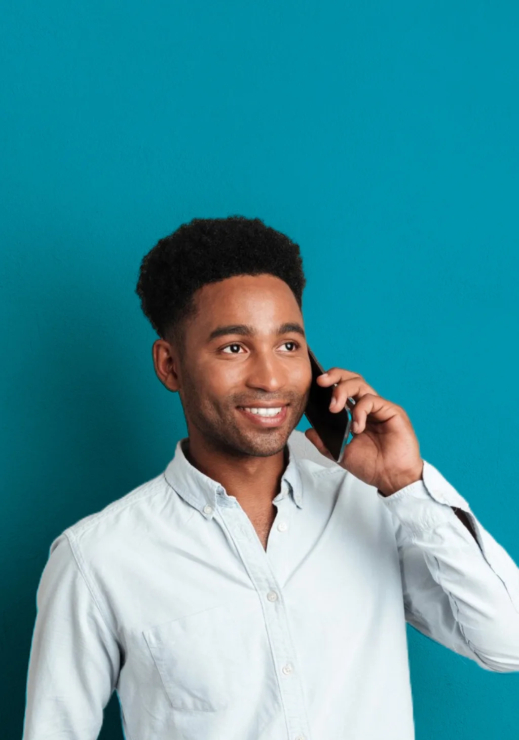 A smiling man holding a phone to his ear.