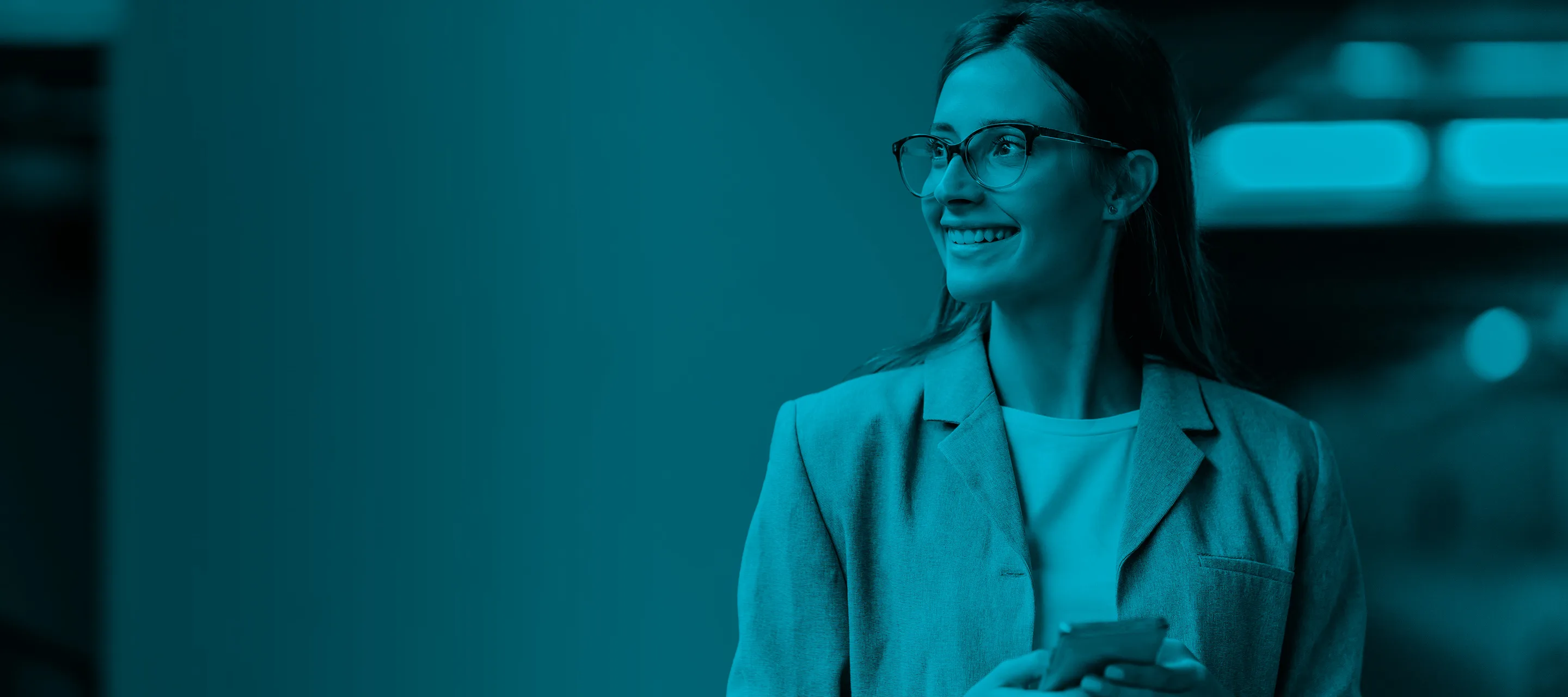 Smiling woman wearing glasses and a blazer, looking to the side.