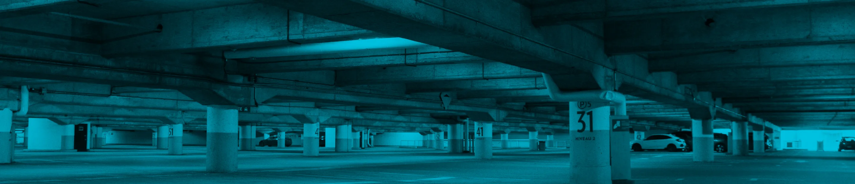 Wide view of an empty indoor parking structure with concrete pillars.