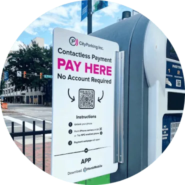 A contactless parking payment sign from CityParking Inc. displays 'PAY HERE' in bold pink text, with instructions below and a QR code in the center.